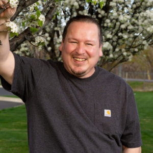 Ted Bradford leans against a flowering tree